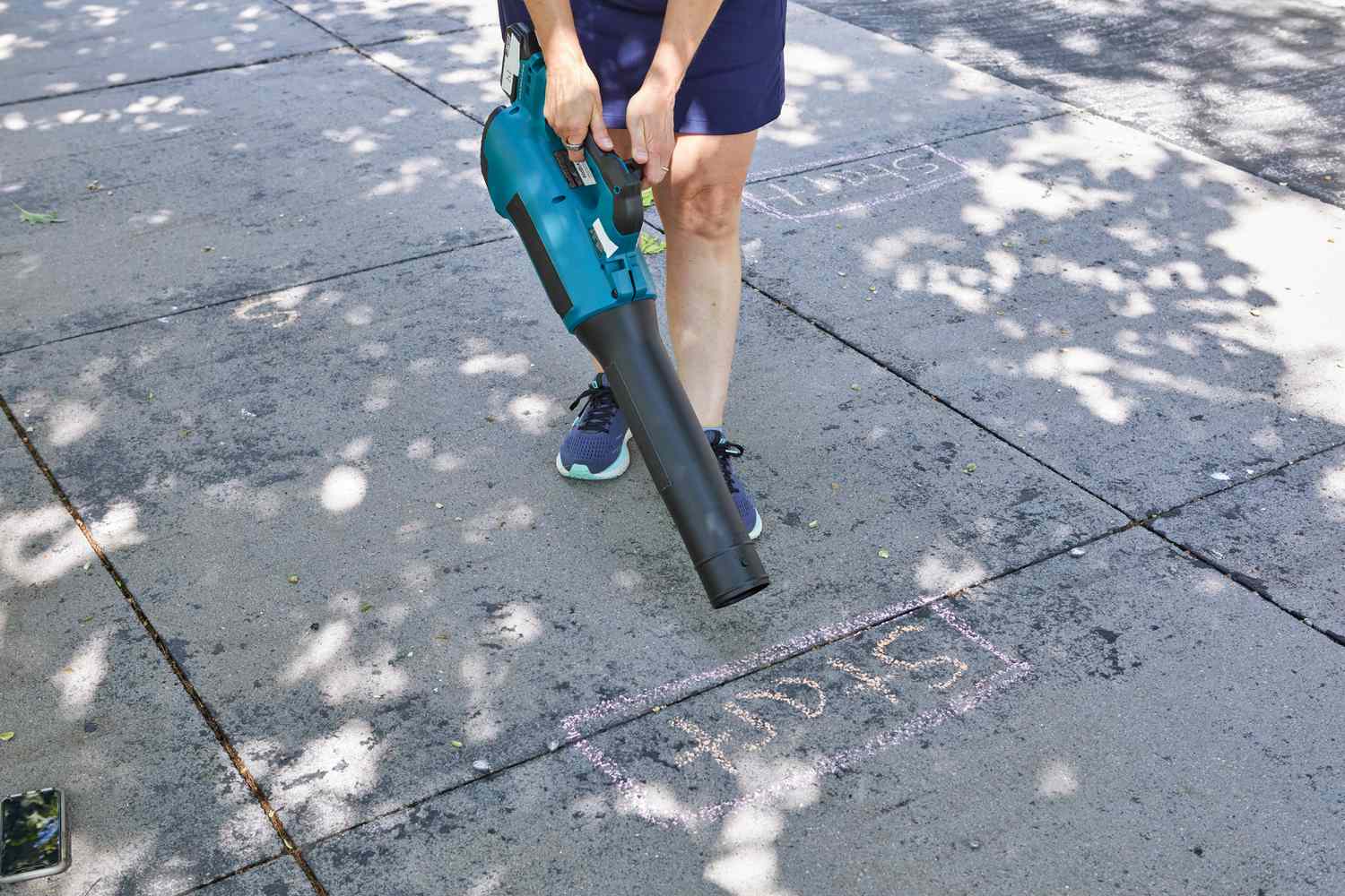 Person using Makita XBU03SM1 18V LXT Lithium-Ion Brushless Cordless Blower Kit on a walkway