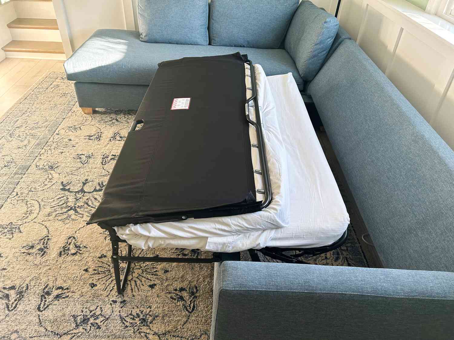 Apt2B Tuxedo 2-Piece Sleeper Sectional partially open mattress displayed on a patterned rug